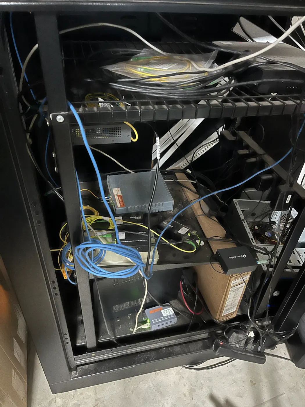 Rack do Santuário São Miguel Arcanjo desorganizado, com equipamentos e cabos soltos