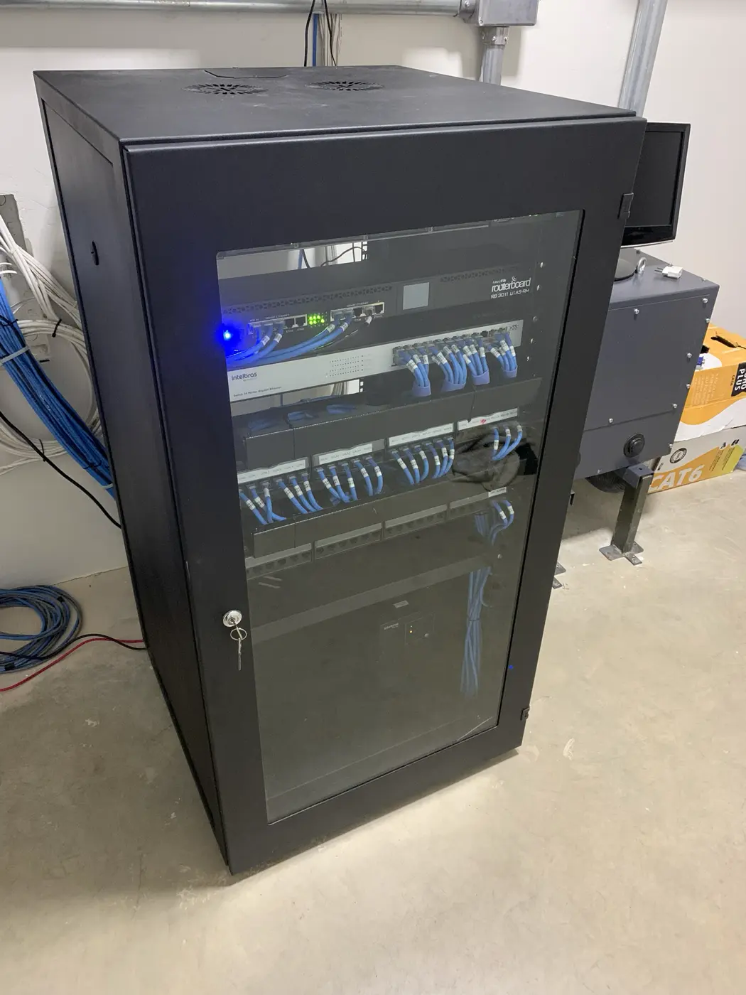 Rack da Clínica Sermed fechado, com cabeamento organizado e equipamentos em operação